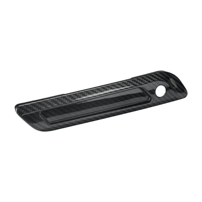 Angled left view of a carbon fiber saddlebag latch cover designed for a custom Harley Touring bagger build.