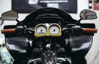 Photo by Anthony Mojica. RF7 Carbon Fiber Dual Gauge Bezel shown with light gold gauge rings. Gauges not included; designed to work with stock gauges on 2014-2023 Road Glide models.